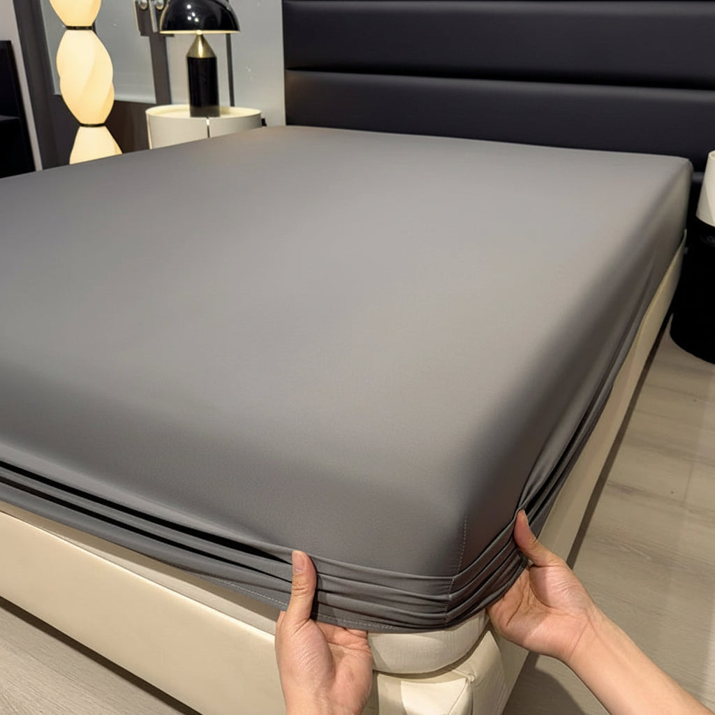 A gray fitted bed sheet is shown on a bed in a bedroom setting, with a person's hands pulling the corner of the sheet to demonstrate elasticity. The text 'Only bedsheet' is overlaid at the top.